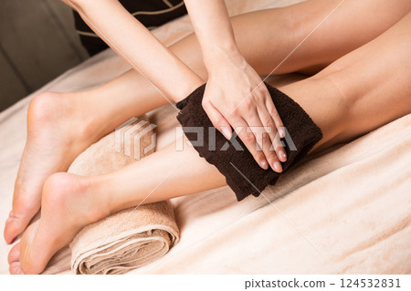 一名年輕的亞洲女子正在用毛巾擦拭腿部。 124532831