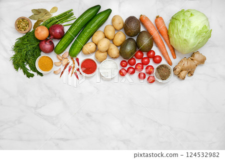 An assortment of vibrant farm vegetables and fresh herbs on a marble surface 124532982