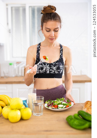 Sportive woman eating vegetable salad at home 124533055