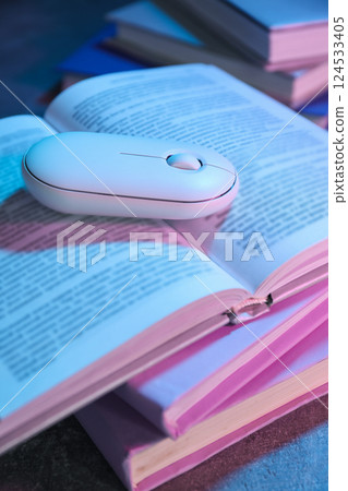 Books with a computer mouse, on a dark background. 124533405
