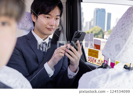 Businessman using a smartphone in the back seat of a taxi 124534099