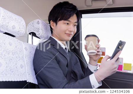 Businessman using a smartphone in the back seat of a taxi Businessman using a smartphone in the back seat of a taxi 124534106