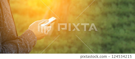 A man holding a smartphone with a green-themed interface, illuminated by a soft lens flare. The blank copy space makes it ideal for advertisements, app promotions, or messaging concepts A man holding a smartphone with a green-themed interface, illuminated by a soft lens flare. The blank copy space makes it ideal for advertisements, app promotions, or messaging concepts 124534215