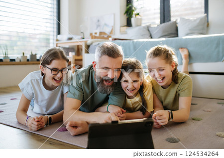 Portrait of father with three daughters watching tv show on tablet. Portrait of father with three daughters watching tv show on tablet. 124534264