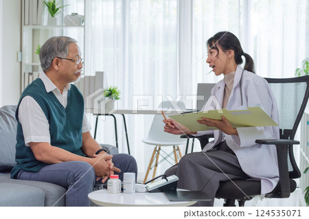 Doctor Reviewing Medical File While Interviewing Elderly Patient at Clinic or Hospital 124535071