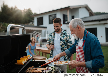 Father-in-law and son-in-law preparing food for a family barbecue. 124536670