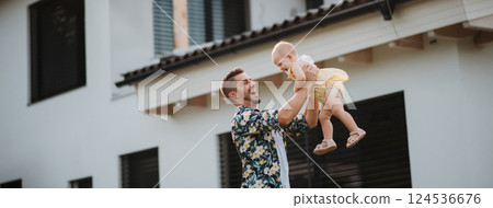 Happy father playing with his baby daughter in the backyard. 124536676