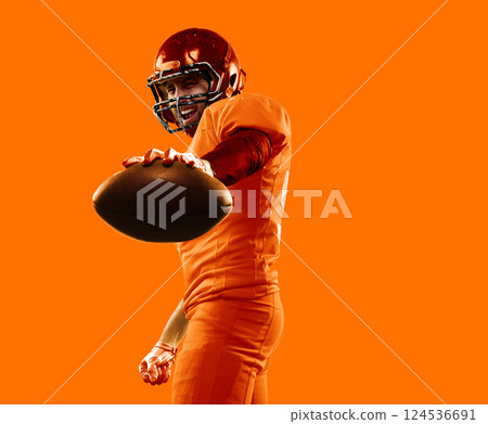 Energetic collage. Intense rugby athlete presenting ball, orange uniform blending into vibrant background. Concept of professional sport 124536691
