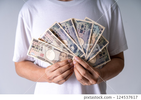 Hands grasping Yen bills in moody lighting: Closeup of 1000 and 10000 notes illustrates financial power and societal tensions in Japan Hands grasping Yen bills in moody lighting: Closeup of 1000 and 10000 notes illustrates financial power and societal tensions in Japan 124537617