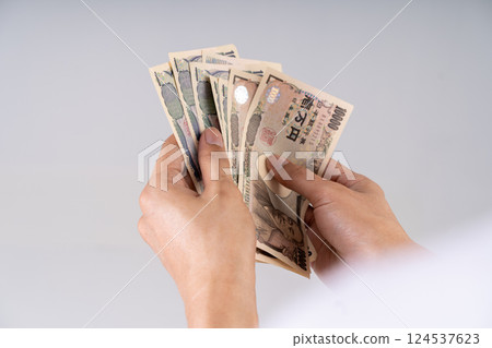 Detailed shot of Yen banknotes being counted: Illustrates financial decision-making and monetary interactions in Japanese economy Detailed shot of Yen banknotes being counted: Illustrates financial decision-making and monetary interactions in Japanese economy 124537623