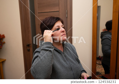 Applying mascara in a cozy home setting during the afternoon light, a moment of self-care and preparation for the day ahead unfolds in the quiet comfort of a personal space Applying mascara in a cozy home setting during the afternoon light, a moment of self-care and preparation for the day ahead unfolds in the quiet comfort of a personal space 124538231