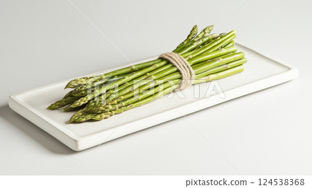 Fresh Green Asparagus Bundled with Twine on White Rectangular Tray. Concept of Healthy Eating, Organic Vegetables, Farm Fresh Produce, Gourmet Cooking Ingredient, White Background 124538368
