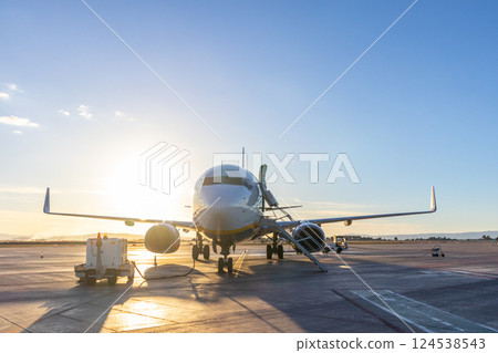 Commercial passengers airplane on airport runway in sunset. 124538543