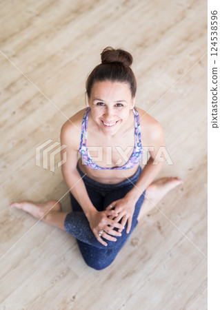 Cheerful fit sporty active girl in fashion sportswear sitting on the floor in yoga studio. Active urban lifestyle. 124538596