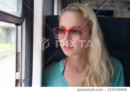 Happy smiling woman looks out from window traveling by train on most picturesque train road in Sri Lanka Happy smiling woman looks out from window traveling by train on most picturesque train road in Sri Lanka 124538660