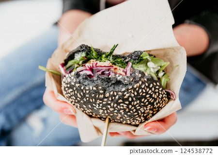 Close up of woman hands holding delicious organic salmon vegetarian burger on open air beer an burger urban street food festival in Ljubljana, Slovenia Close up of woman hands holding delicious organic salmon vegetarian burger on open air beer an burger urban street food festival in Ljubljana, Slovenia 124538772