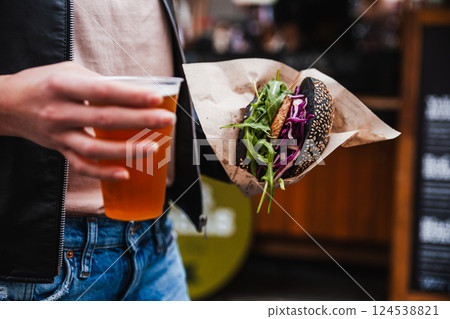 Close up of woman hands holding delicious organic salmon vegetarian burger and homebrewed IPA beer on open air beer an burger urban street food festival in Ljubljana, Slovenia Close up of woman hands holding delicious organic salmon vegetarian burger and homebrewed IPA beer on open air beer an burger urban street food festival in Ljubljana, Slovenia 124538821