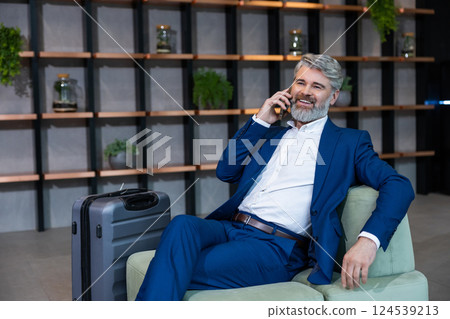 Good-looking well-dressed bearded man sitting in the chair and talking on the phone 124539213
