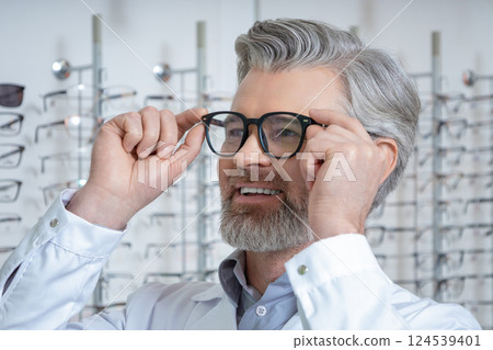 Portrait of a mature bearded caucasian man tryin on new glasses Portrait of a mature bearded caucasian man tryin on new glasses 124539401