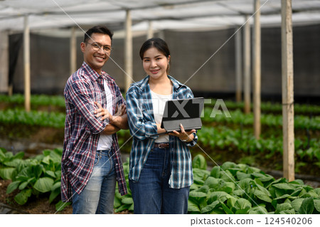 Confident farmers using digital tablet in smart greenhouse Confident farmers using digital tablet in smart greenhouse 124540206