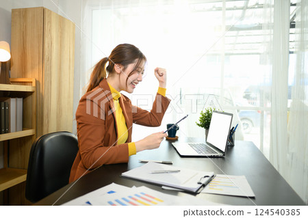 Excited businesswoman reading great news on digital tablet celebrating success in a bright workspace 124540385