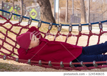 Caucasian child of eight nine years with closed eyes and arms behind head resting on hammock Caucasian child of eight nine years with closed eyes and arms behind head resting on hammock 124540635