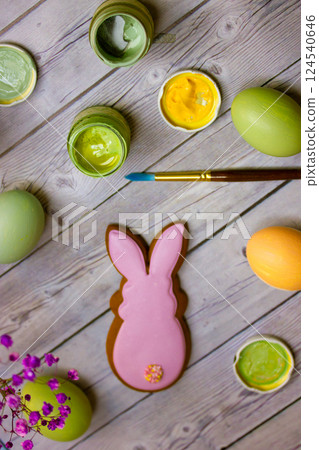 Preparing for the Easter holidays: painted eggs, gingerbread bunny-shaped cookies and paint brushes lie on a wooden table top view and selective focus 124540646