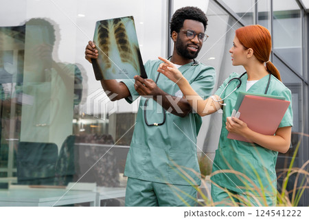 Female doctor discussing x ray picture with male physician in hospital office Female doctor discussing x ray picture with male physician in hospital office 124541222