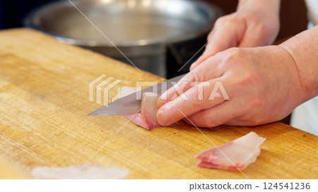 A Japanese chef cutting a yellowtail A Japanese chef cutting a yellowtail 124541236