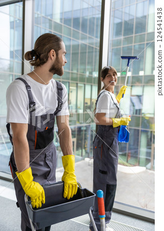 Young people cleaning the office and looking contented 124541438
