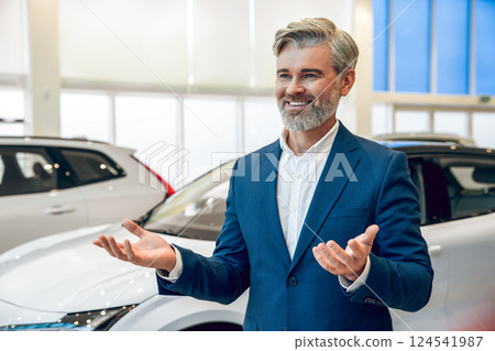 Professional salesman presenting new car in dealership showroom Professional salesman presenting new car in dealership showroom 124541987