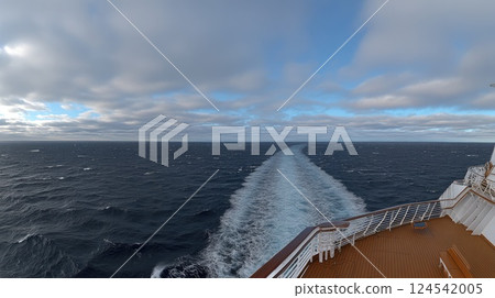 Experience the thrill of a yacht slicing through huge ocean waves, leaving a white foam trail against a backdrop of blue skies 124542005