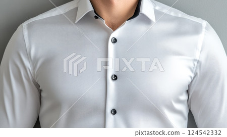 A stylish man adjusts his shirt cuffs while confidently posing in black pants and a white slim-fit shirt against a gray background 124542332