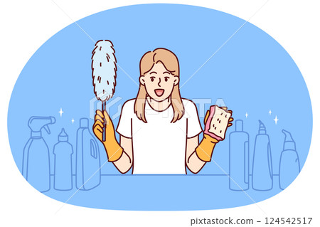 Cheerful woman housekeeper holds cleaning brush in hands, standing near table with detergents Cheerful woman housekeeper holds cleaning brush in hands, standing near table with detergents 124542517