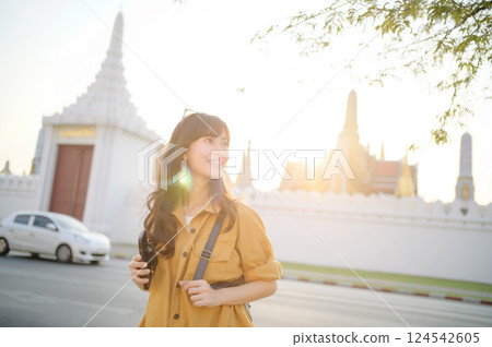Traveler asian woman in her 30s stands bathed in the golden glow of sunset, embracing the freedom of exploration. on summer holiday weekend vacation trip in Bangkok, Thailand Traveler asian woman in her 30s stands bathed in the golden glow of sunset, embracing the freedom of exploration. on summer holiday weekend vacation trip in Bangkok, Thailand 124542605