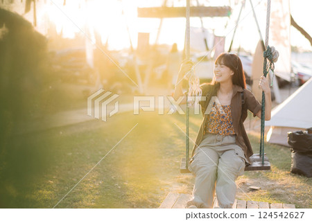 asian woman sitting in swing at camping site. 124542627