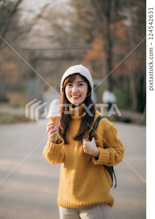 Cheerful Asian woman in yellow sweater enjoying tasty ice-cream indoors. Lifestyle portrait of a cute girl in a fashionable outfit, expressing joy and happiness. Cheerful Asian woman in yellow sweater enjoying tasty ice-cream indoors. Lifestyle portrait of a cute girl in a fashionable outfit, expressing joy and happiness. 124542631