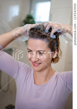 Woman applying purple hair dye at home in the bathroom 124542930