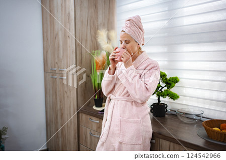Woman enjoying morning coffee with facial mask in kitchen 124542966