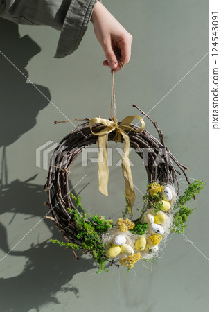 Woman hand Handmade Easter wreath made of sustainable materials decorations in yellow color. Homemade decor Easter celebration gift present ideas. Copy space 124543091