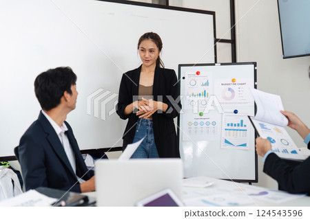 Dynamic Team Interaction and Budget Analysis. A woman explains key budget metrics to attentive colleagues. 124543596