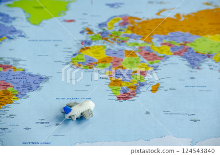 Top view of small toy airplane placed on a world map representing travel or global exploration. Travel and destination concept Top view of small toy airplane placed on a world map representing travel or global exploration. Travel and destination concept 124543840