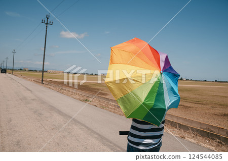 man carrying a rainbow umbrella on his shoulders man carrying a rainbow umbrella on his shoulders 124544085
