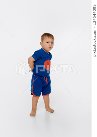 Child standing with toothbrush behind back, looking sideways with playful face isolated on white background. Child standing with toothbrush behind back, looking sideways with playful face isolated on white background. 124544099