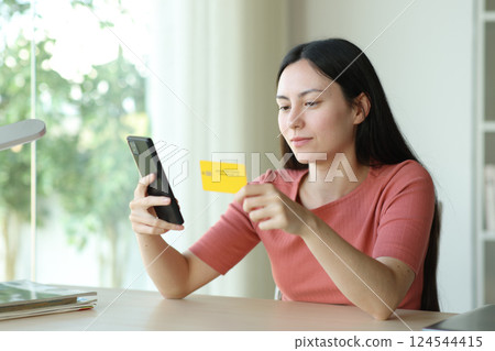 Asian woman using phone and card buying online 124544415