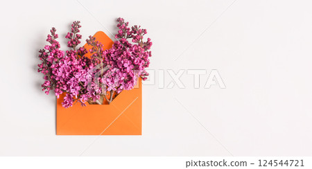 Orange envelope with spring flowers purple lilac on gray background. Invitation to the holidays. Flat lay. 124544721