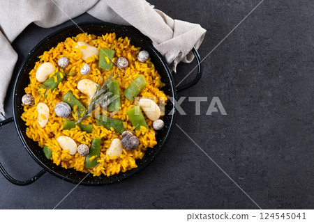Traditional Valencian paella with rabbit, chicken, garrofon beans, snails, Moroccan green beans and saffron on black background Traditional Valencian paella with rabbit, chicken, garrofon beans, snails, Moroccan green beans and saffron on black background 124545041