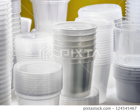 Clear plastic cups and containers stacked neatly on a table in a bright space suitable for events or gatherings Clear plastic cups and containers stacked neatly on a table in a bright space suitable for events or gatherings 124545467