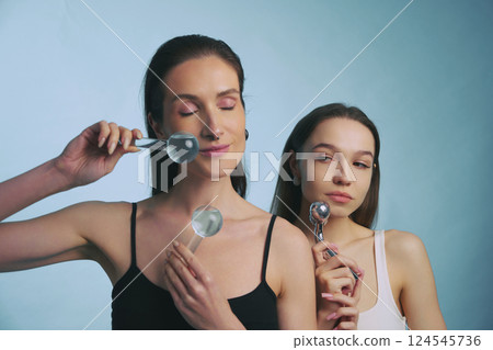 Women practicing skincare techniques with beauty tools in a studio setting Women practicing skincare techniques with beauty tools in a studio setting 124545736
