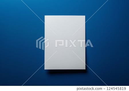 Top view of a blank sheet of white textured watercolor paper on a textured dark blue background. Suitable for advertising related to creativity, art, education and stationery. Place for text, logo 124545819